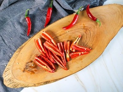 Red chillies sliced length ways with the seeds removed on a wooden chopping board