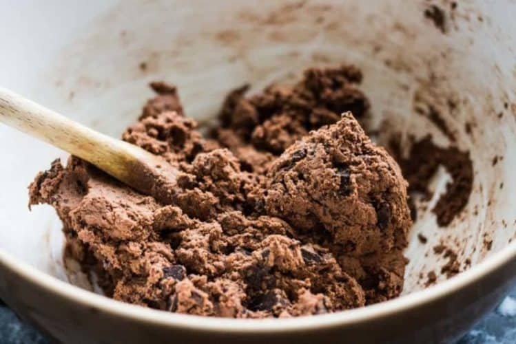 Double chocolate chip biscuit dough in a bowl with a wooden spoon