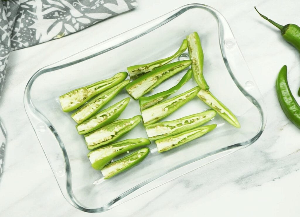 Green chilli halves spread out in a glass dish