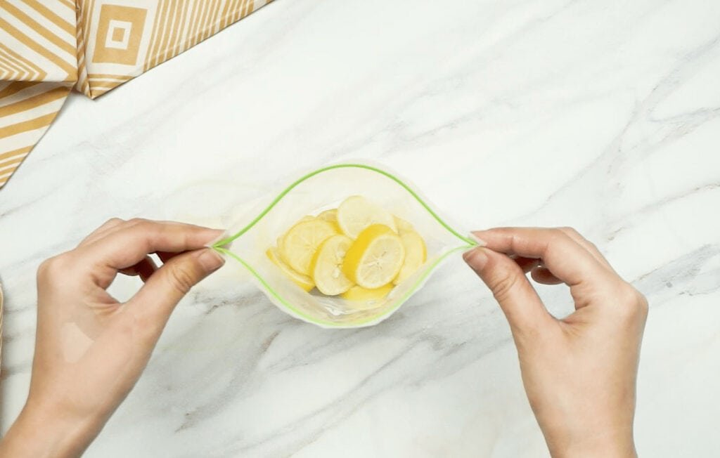 Lemon slices inside an open freezer bag being held by a woman's hands