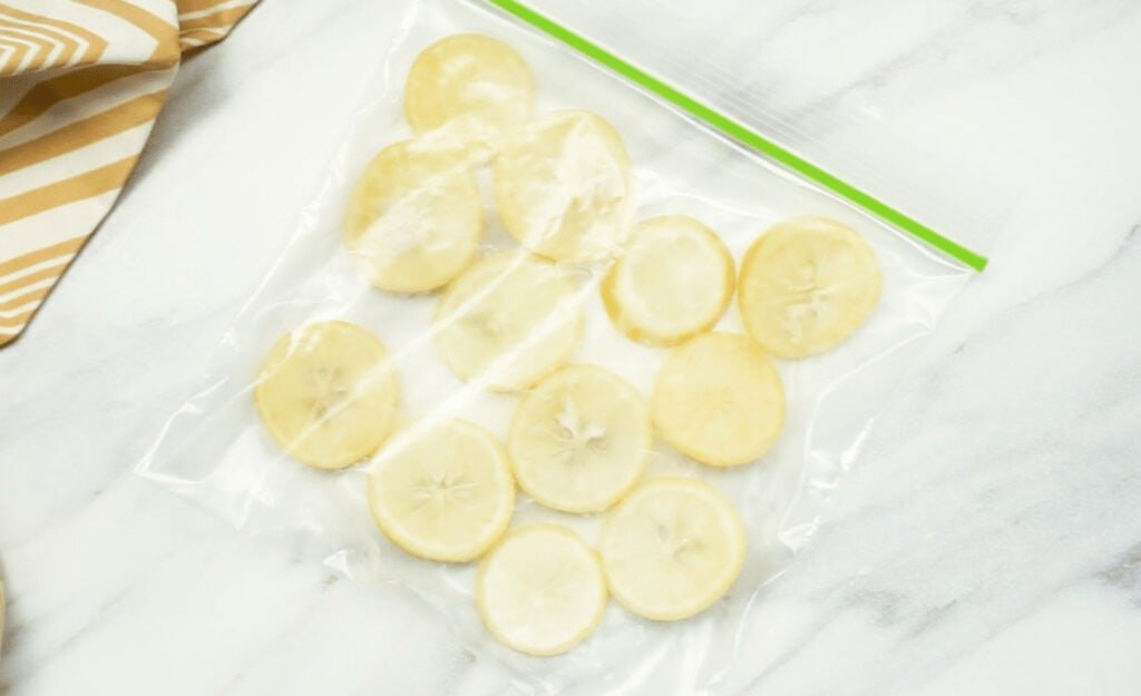 Frozen lemon slices spread out inside a sealed freezer bag.