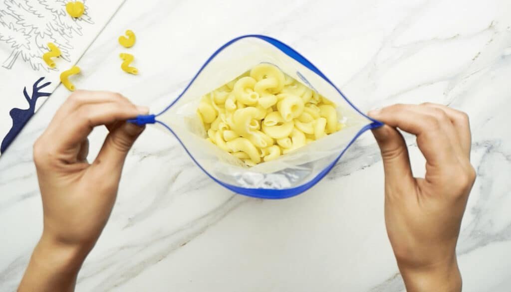 Macaroni pasta placed into a freezer bag with a blue seal ready for freezing