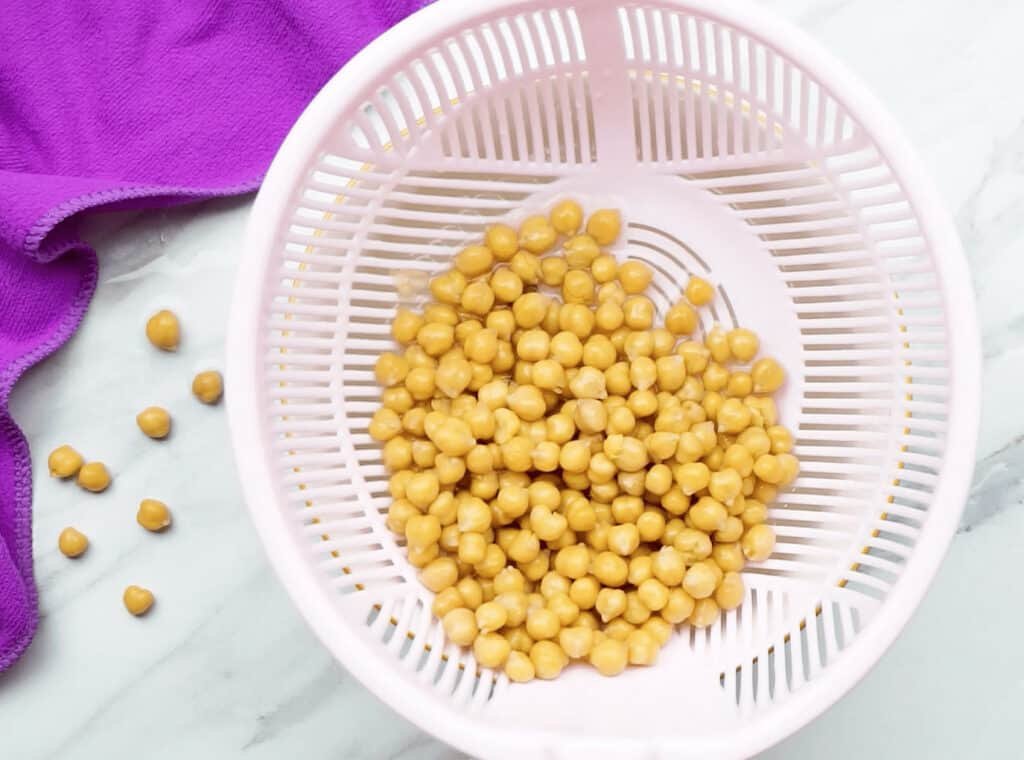 Chickpeas being drained in a white colander