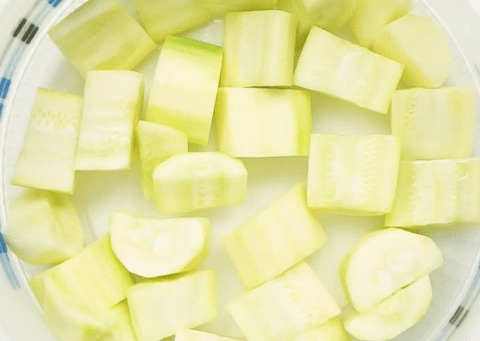 Blanched courgette pieces in a white bowl ready to be frozen 