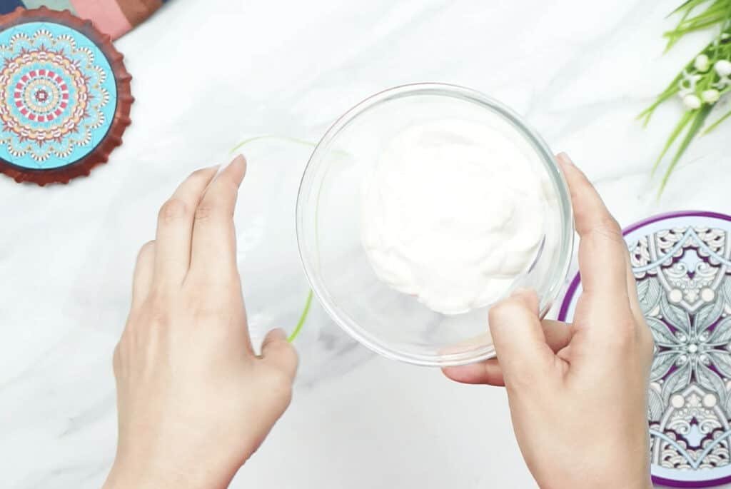 Double cream in a glass bowl being poured into a freezer bag