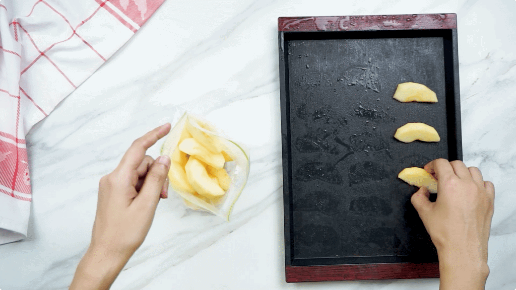 Apple sliced being remove from a tray and bagged up by a woman's hands