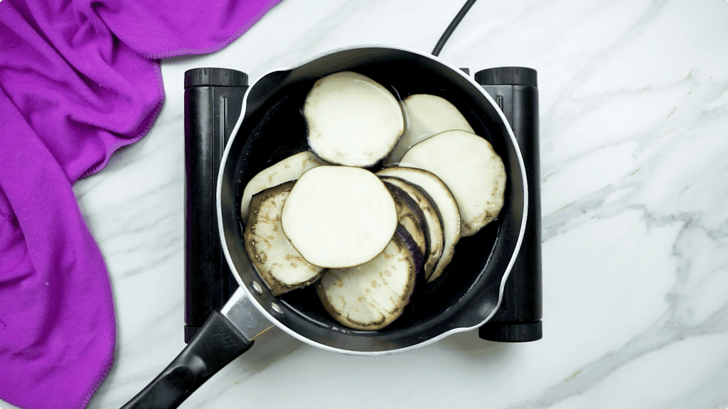 Aubergine being blanch in a black pot of water