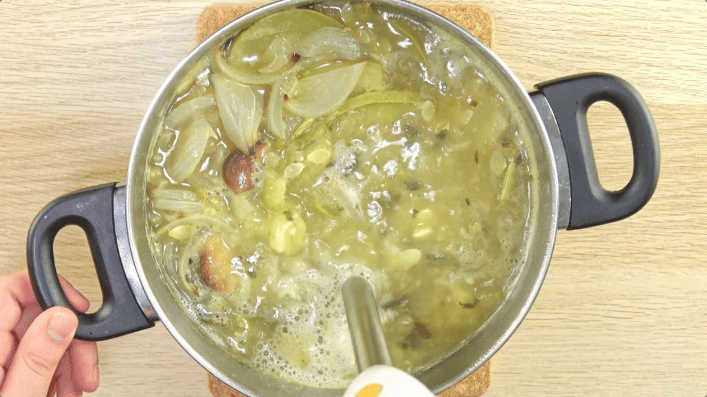 A stick blender, blitzing courgettes, onion, garlic and stock