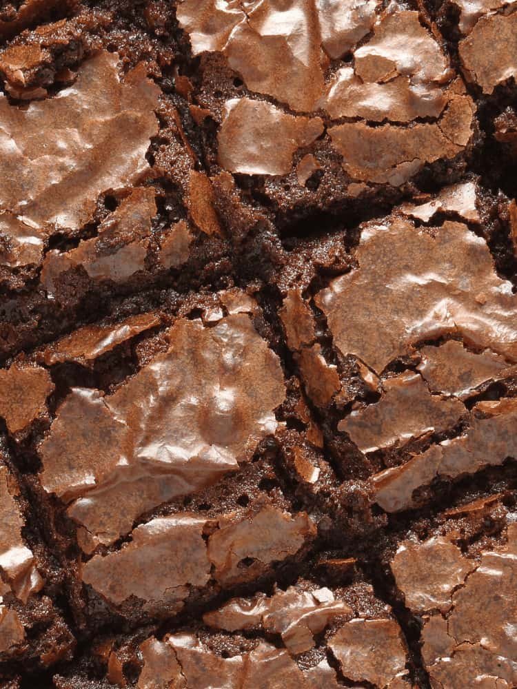 Gooey chocolate brownies side-by-side with cracked chocolate tops taking up the entire photo with no background