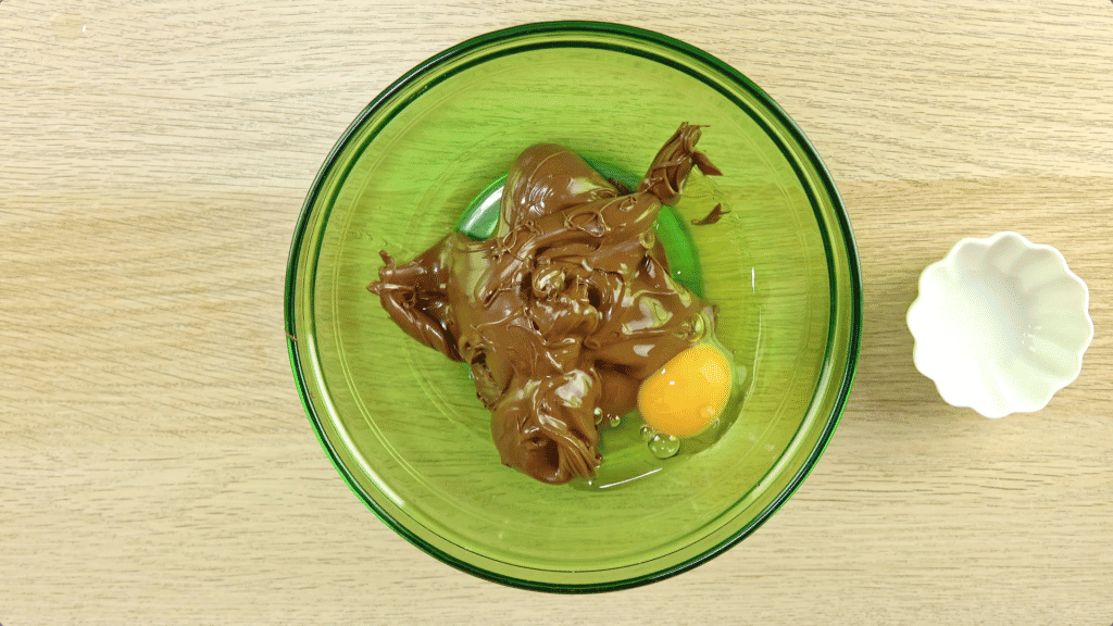 Nutella and an egg in a green-tinted glass bowl