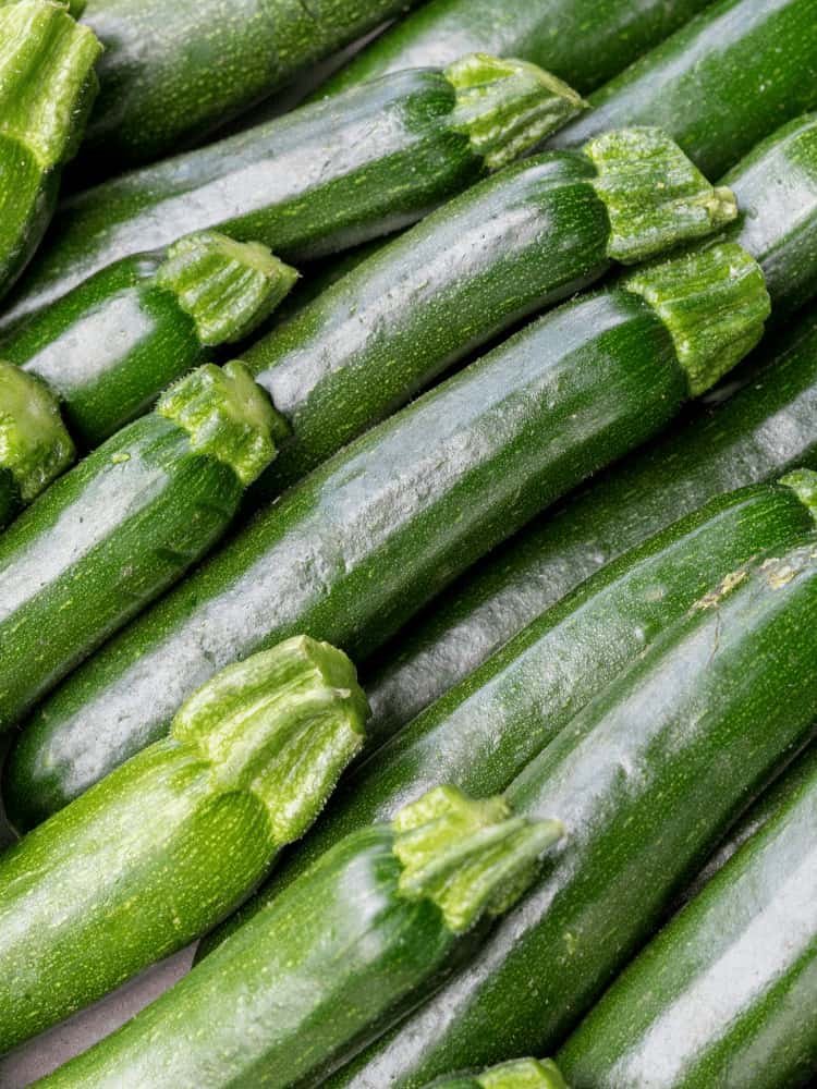 A full photo of green courgettes or zucchini laid on top of each other with no background