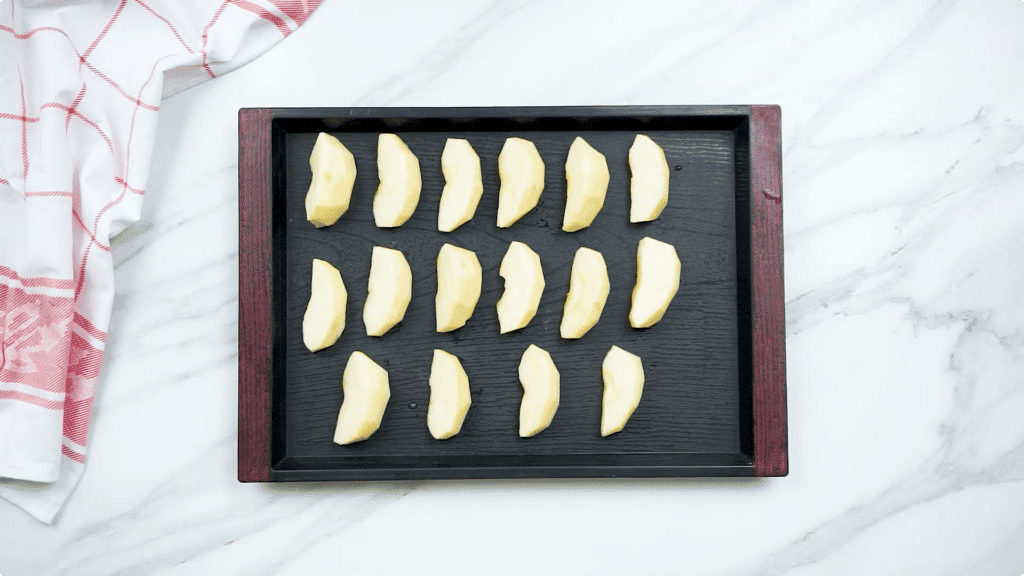 Apple slices spread out on a tray for freezing