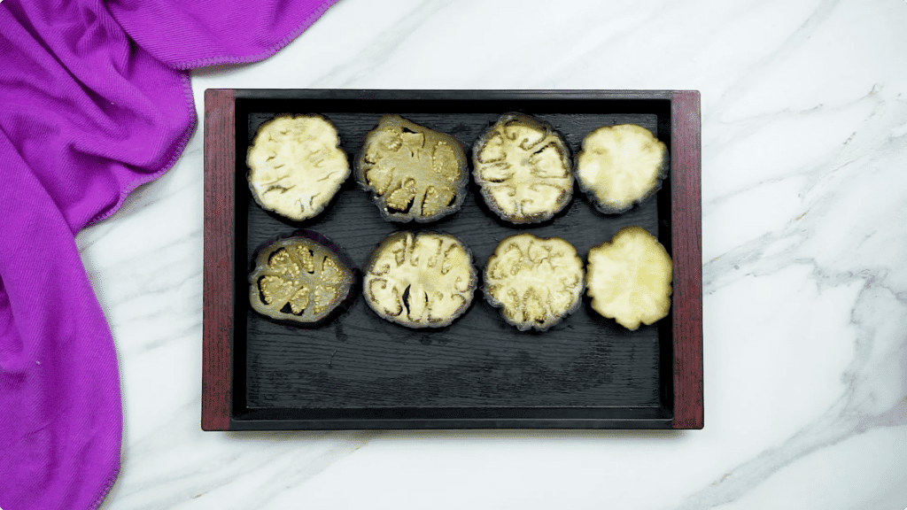 Sliced aubergine spread out on a baking tray