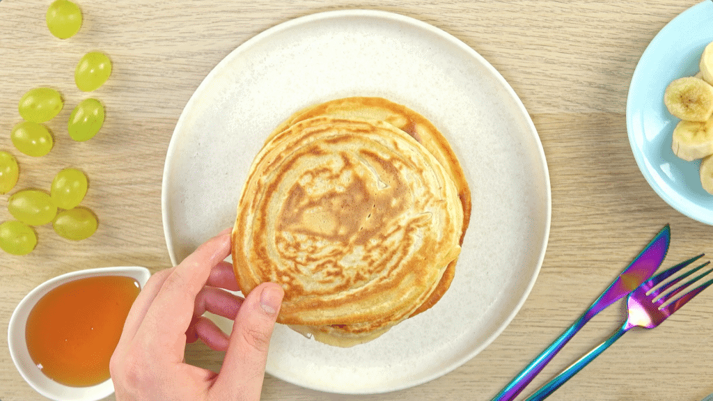 3 ingredient pancakes being stacked onto a plate with toppings around it on individual plates