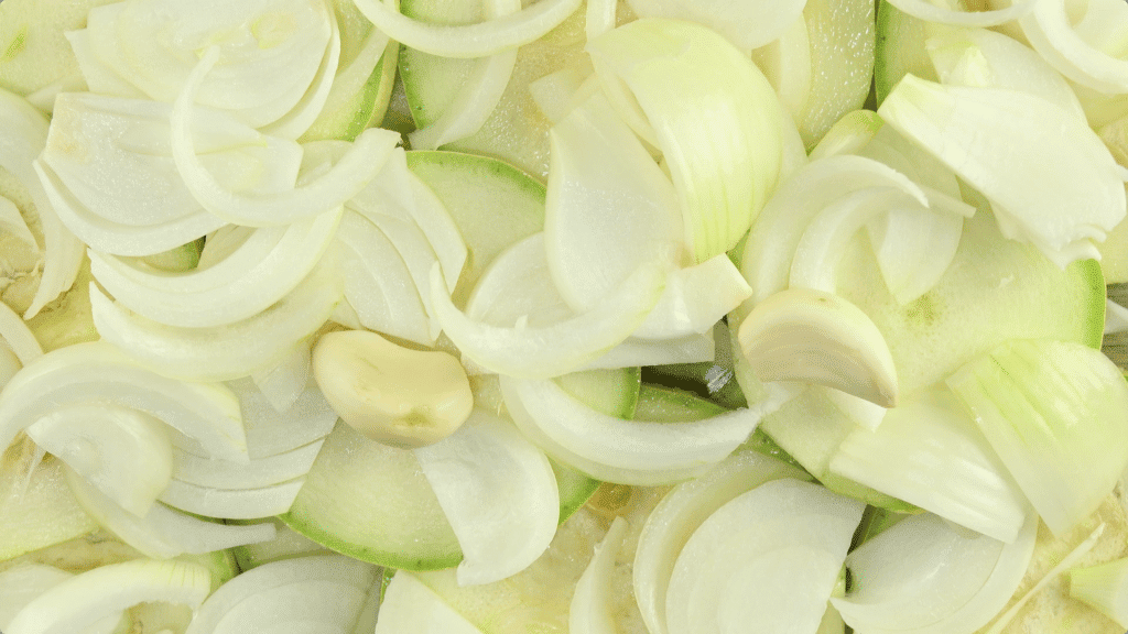 Sliced courgette, onions and garlic layered on top of each other