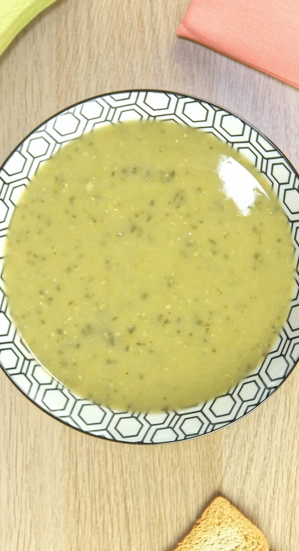 Bowl of roasted courgette soup on a wooden background