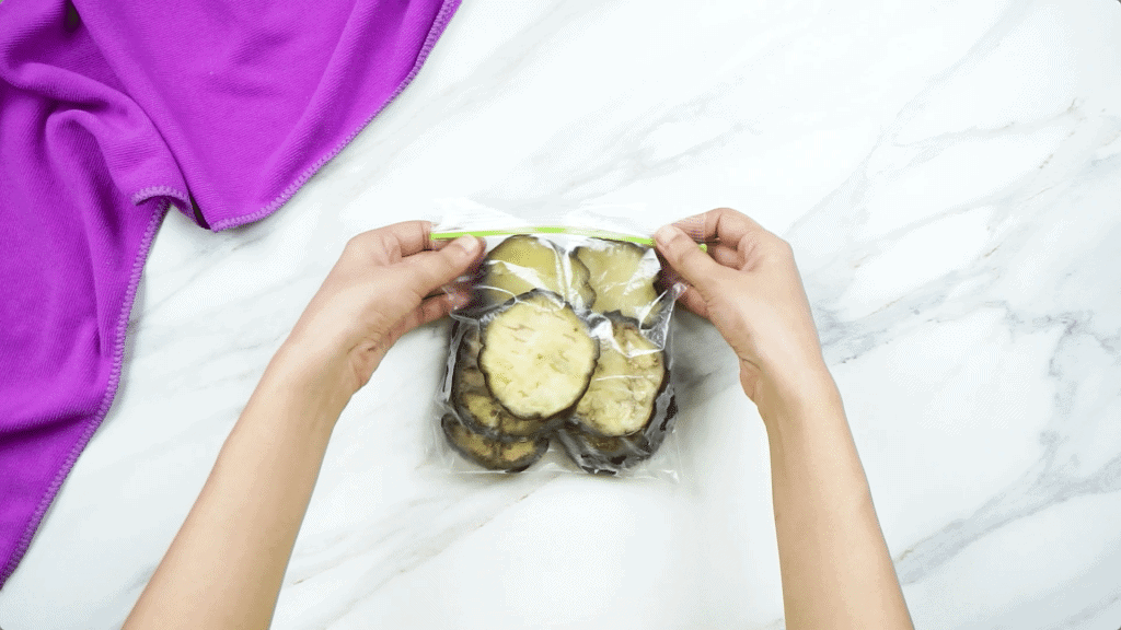 Frozen aubergine slices inside a clear plastic freezer bag