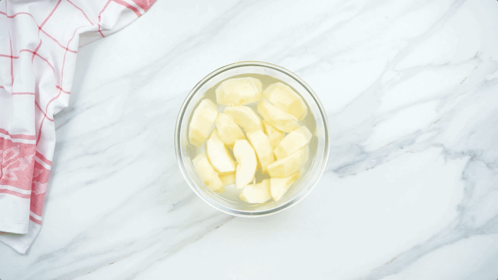 Peeled, sliced apples in a lemon juice bath in a glass bowl before freezing