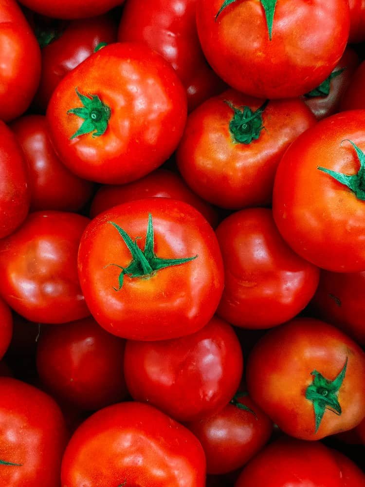 Bright red tomatoes piled on top of each taking up the whole photo frame